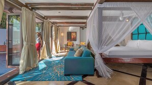 Een kamer met een bed, een slaapbank en een glazen deur naar buiten.