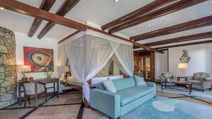 Een slaapkamer met een hemelbed, een zithoek met een bank en fauteuils, en een eethoek met een tafel en stoelen.
