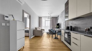 Una cocina moderna con comedor, suelo de madera y un sofá gris.