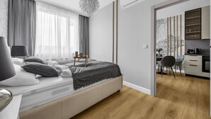 Un dormitorio moderno con una cama grande, mesitas de noche y vistas a una cocina.