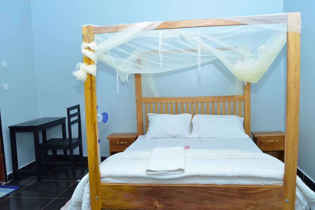 Un lit en bois avec un baldaquin, des oreillers blancs et une table de chevet.