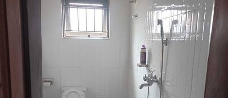 Un baño con inodoro, lavamanos, ducha y ventana.
