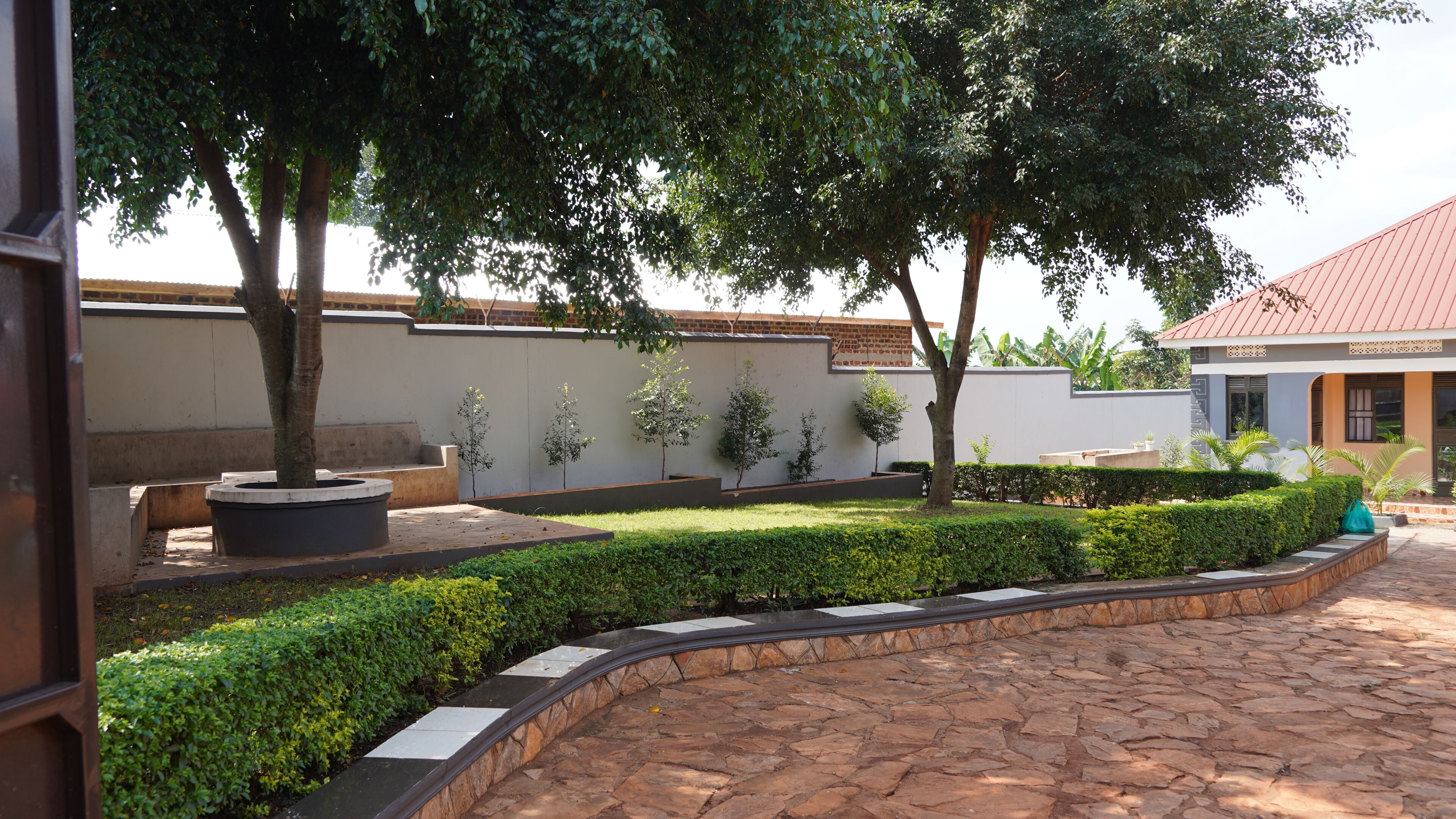 A courtyard with a stone pathway, a bench, and neatly trimmed hedges.