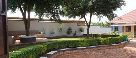 A courtyard with a stone pathway, a bench, and neatly trimmed hedges.