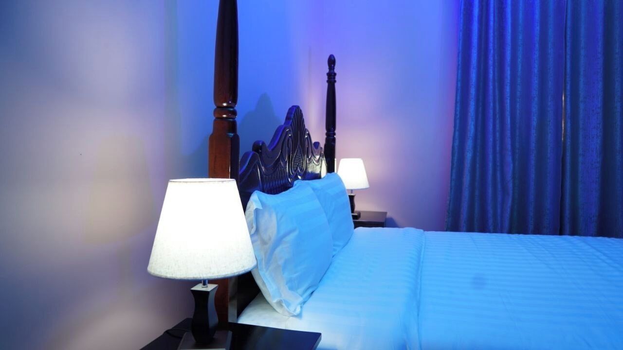 A hotel room with a bed, two bedside lamps, and a curtain.
