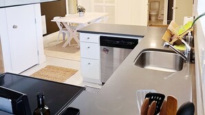 Une cuisine moderne équipée d’un lave-vaisselle, d’un évier et d’un coin repas avec une table et des chaises.