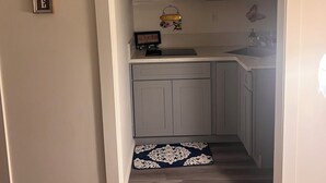 A small kitchen with grey cabinets, a microwave, a sink, and a welcome sign. - Detached Casita  studio charming Perris (Perris)