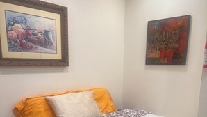 A bedroom with a bed, two pillows, a framed painting, and a second painting on the wall. - Detached Casita  studio charming Perris (Perris)