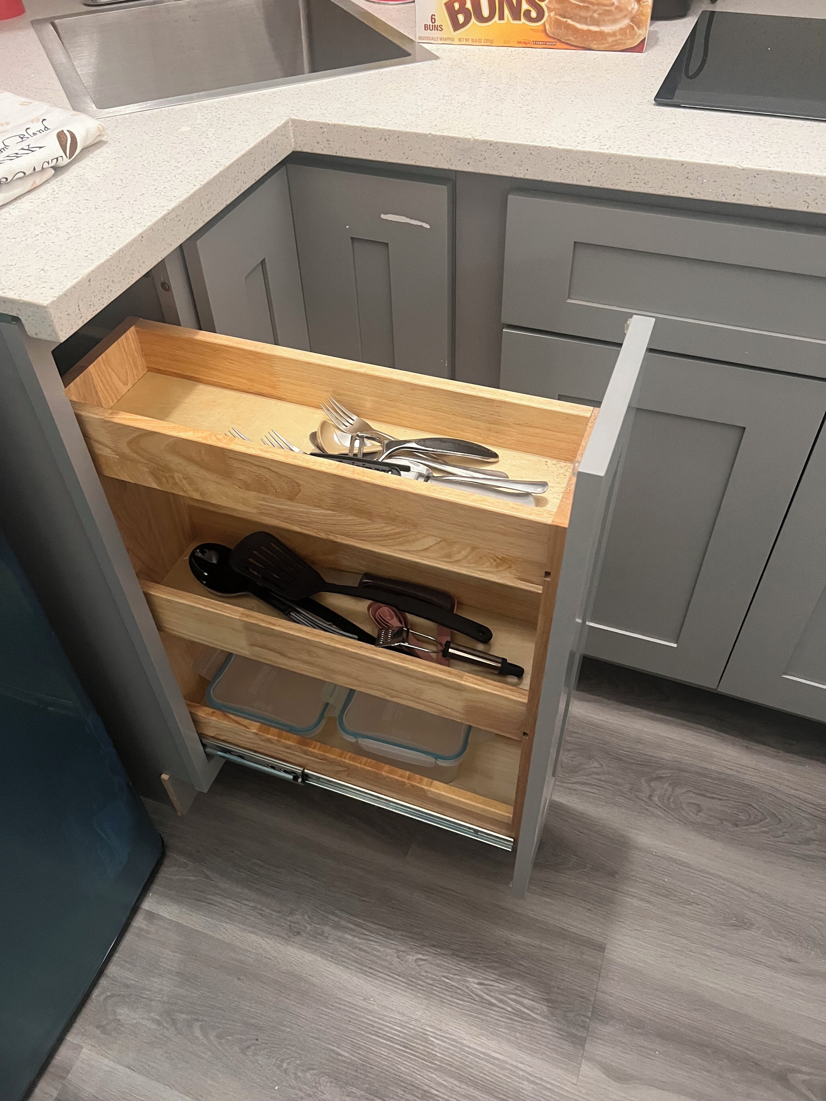 A kitchen with a built-in drawer unit containing utensils and containers.