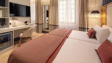 Habitación de hotel con cama, escritorio, silla, televisión y minibar.