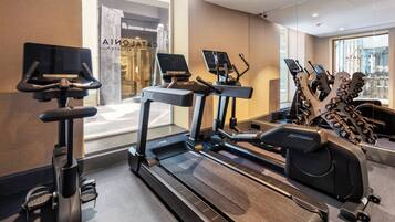 A gym with treadmills, elliptical machines, and dumbbells.