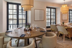 Un comedor con una mesa redonda, sillas y lámparas colgantes.