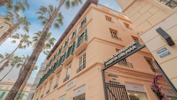 Entrada de un hotel con un cartel que indica 'Hotel Catalina Puerta del Mar' y una reja.