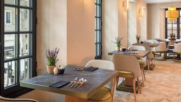 L’intérieur d’un restaurant, avec des tables, des chaises et des plantes en pot.