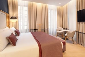 A hotel room with a large bed, a desk, two chairs, a television, and curtains. - Catalonia Puerta Del Mar (Málaga)