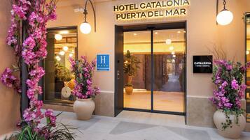 The entrance of Hotel Catalonia Puerta del Mar with a sign indicating it is a hotel.