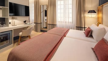 Ein Hotelzimmer mit einem Bett, einem Schreibtisch, einem Sessel, einem Fernseher und einer Minibar.