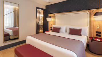 Een hotelkamer met een groot bed, een nachtkastje, een spiegel en een wandlamp.