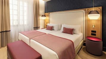A double bed with a patterned bedspread, two bedside lamps, a wooden headboard, and a red bench.