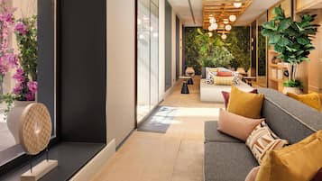 Een moderne woonkamer met een bank, kussens, een salontafel en een decoratieve wand met planten.