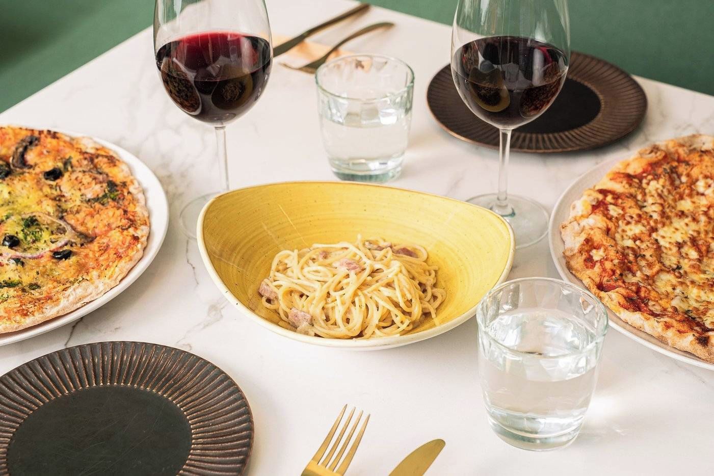 A dining table with plates of food, glasses of water, and cutlery.
