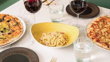 A dining table with plates of food, glasses of water, and cutlery.