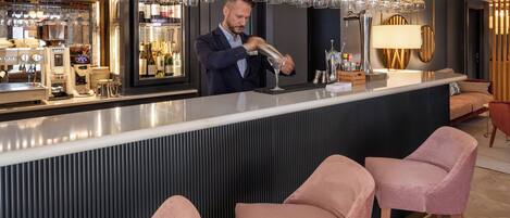 Un espace bar avec un barman préparant des boissons, un réfrigérateur à vin et des tabourets de bar.