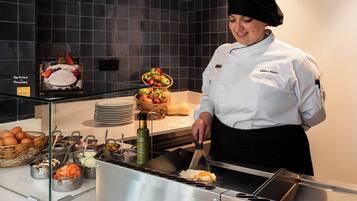 Un chef preparando comida en una cocina, mostrando una variedad de alimentos y ingredientes para el desayuno.