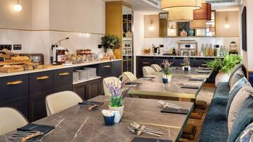 A modern dining area with a long table, chairs, and a sofa.