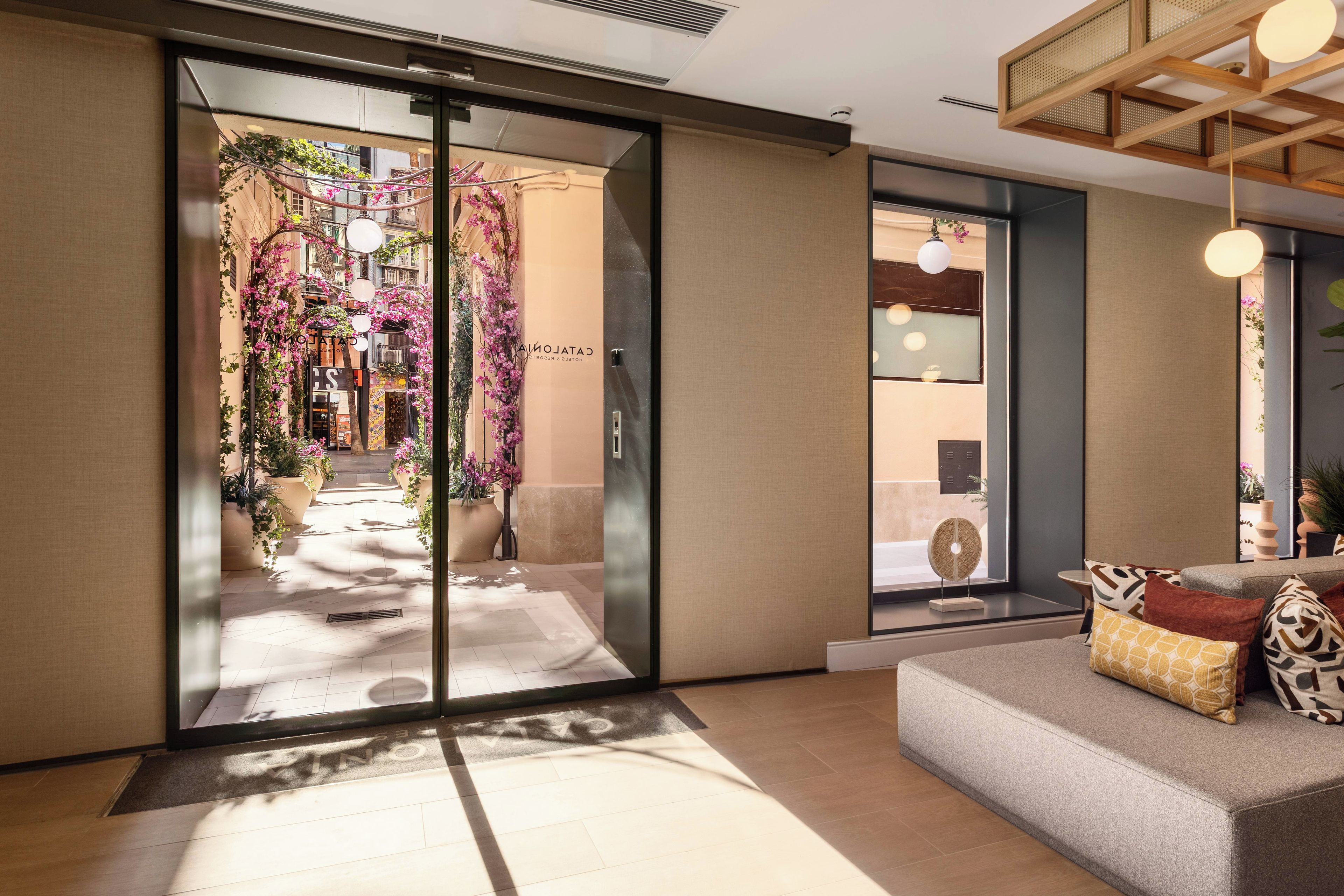 Een hotel lobby met een modern ontwerp, met een receptiebalie, een zithoek en uitzicht op de straat.