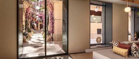 Een hotel lobby met een modern ontwerp, met een receptiebalie, een zithoek en uitzicht op de straat.