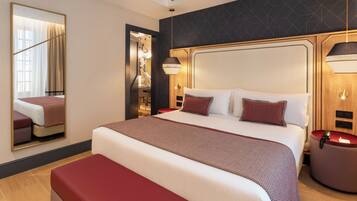 A hotel room with a large bed, a bedside table, a mirror, and a wall-mounted lamp.