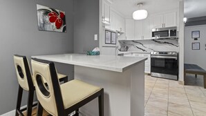 A modern kitchen with white cabinets, a marble countertop, and a built-in oven. - Modern 2-bedroom next to Stampede +17th w/ Parking (Calgary)