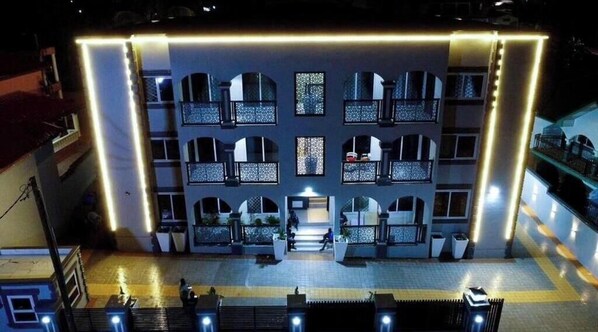 A multi-story hotel with a central courtyard, balconies, and a well-lit entrance.