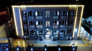 A multi-story hotel with a central courtyard, balconies, and a well-lit entrance.