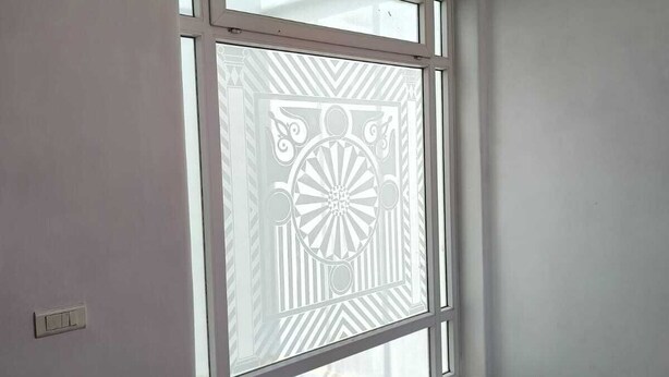 A room with a window featuring a decorative pattern.
