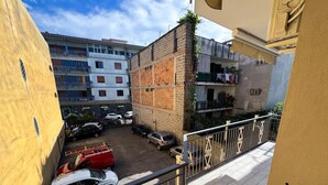 A courtyard with cars parked, a red vehicle, and a building with a balcony. - Domus Ortensia (Boscoreale)