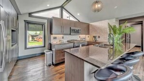 Una cocina moderna con una isla grande, taburetes de bar y vistas al exterior.