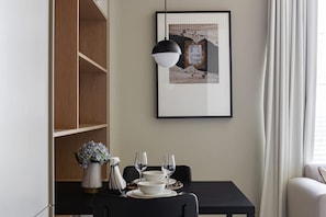 A dining area with a table set for two, a framed picture on the wall, and a pendant light above. - Modern Studio at Upside Living  with Burj Khalifa View by Simply Comfort (Dubai)