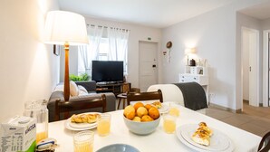 A dining area with a table set for breakfast, including a bowl of oranges, croissants, and juice glasses. - Brisa do Mar in S o Martinho do Porto (Alcobaça)