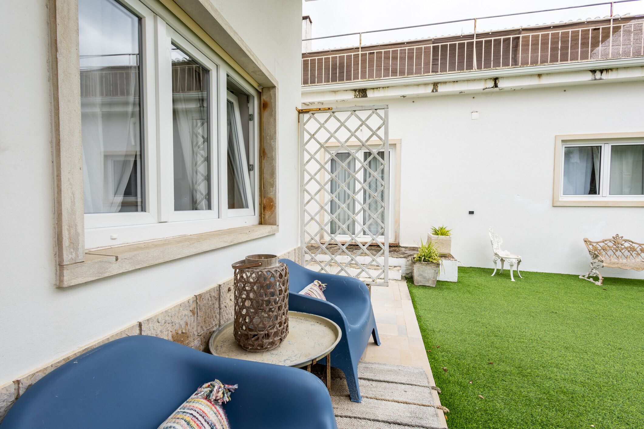A patio with blue seating, a small table, and a decorative metal vase.