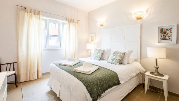 A neatly arranged bedroom with a bed, bedside tables, and a window with curtains. - Brisa do Mar in S o Martinho do Porto (Alcobaça)