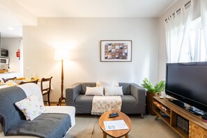 Olohuone, jossa on sohva, sohvapöytä, televisio ja lamppu.