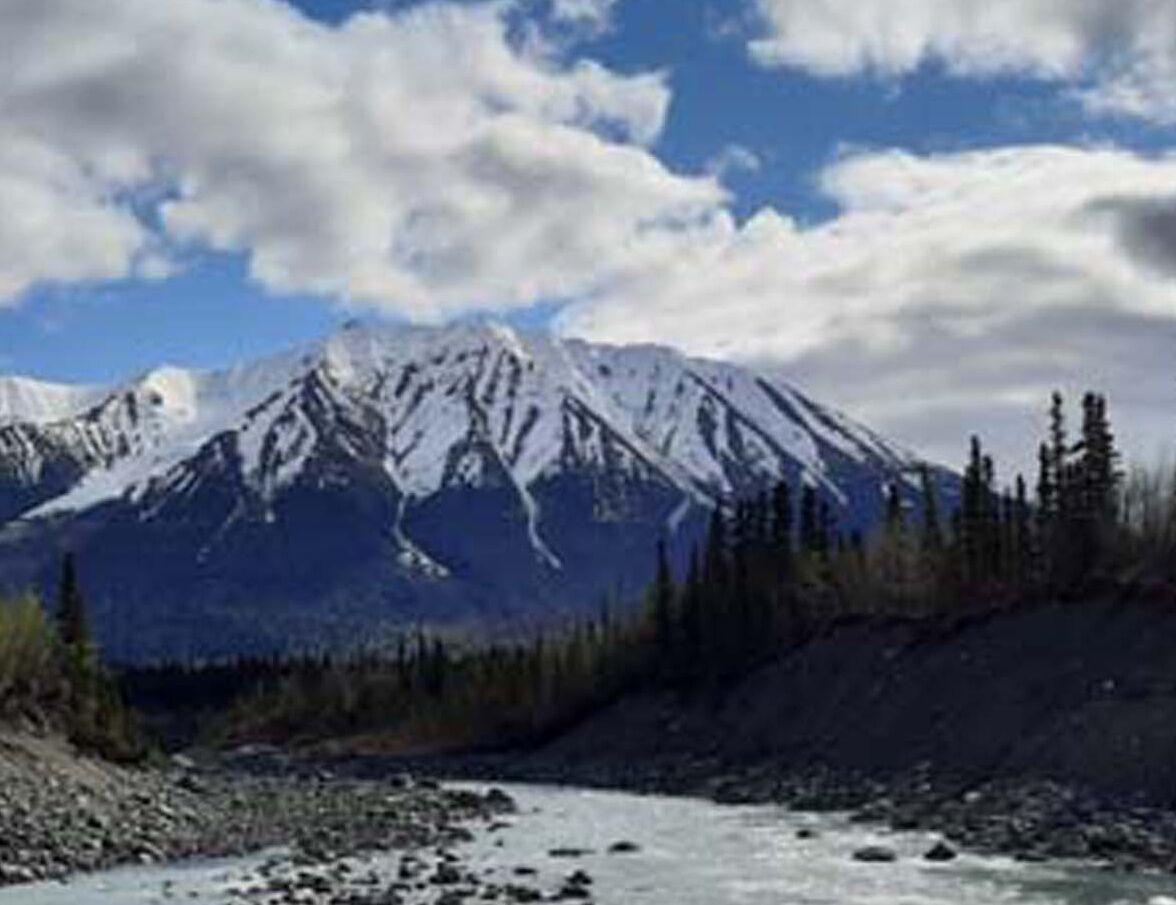 A mountain landscape with snow-covered peaks and a river in the foreground.