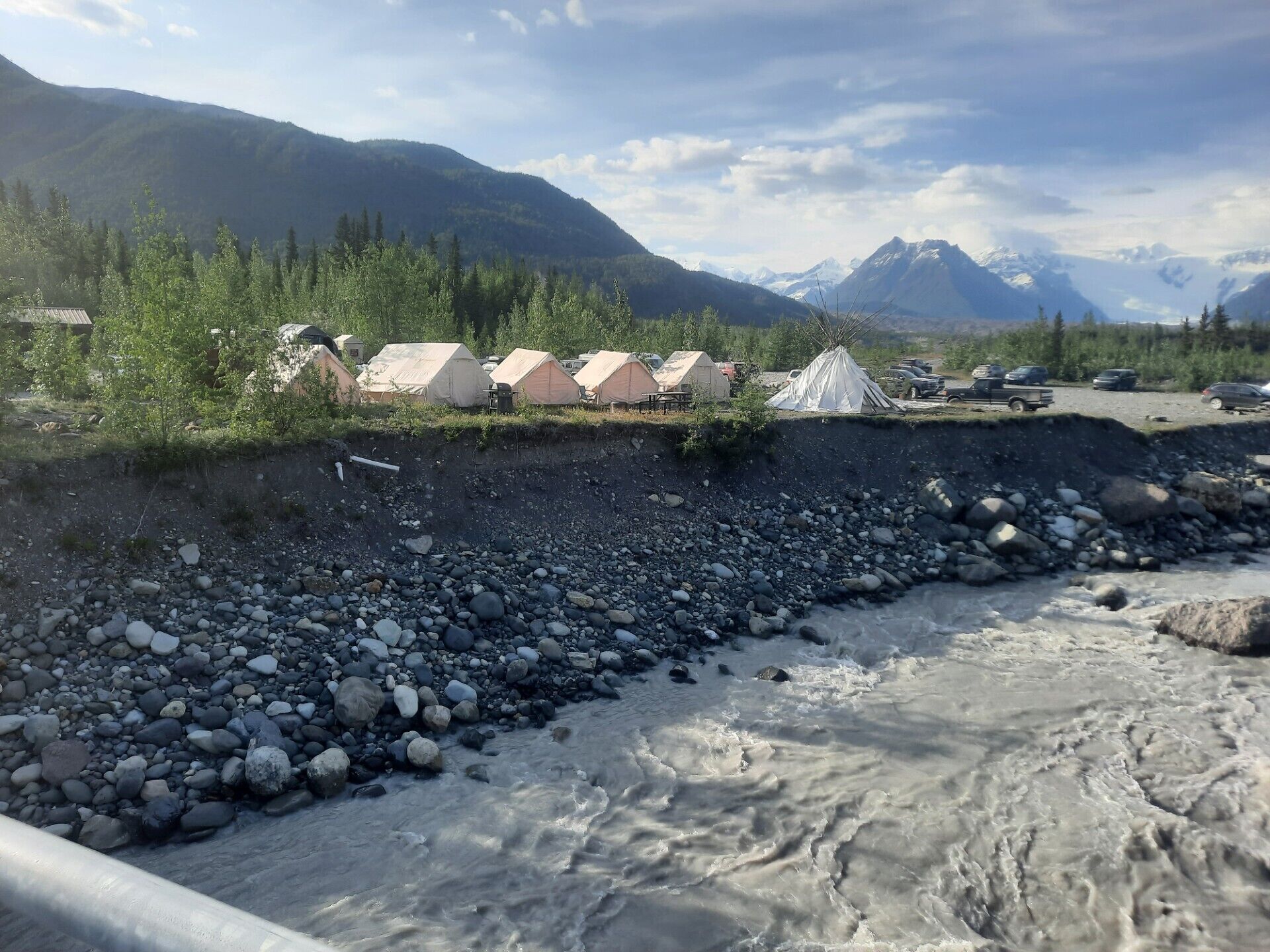 A campsite with tents and a rocky riverbank.