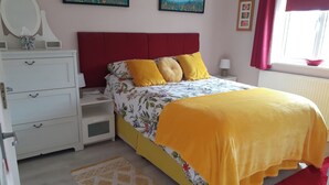 A bedroom with a bed, nightstands, a dresser, and a window with curtains.