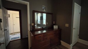 Une pièce comprenant une commode en bois, un grand miroir et un tableau encadré accroché au mur.