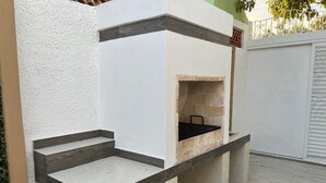 A modern outdoor kitchen with a built-in grill and a small seating area.