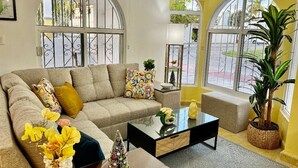 A living room with a sofa, coffee table, and a potted plant.