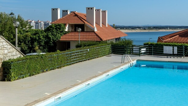 En swimmingpool med krystalklart havudsyn og bygninger i baggrunden.